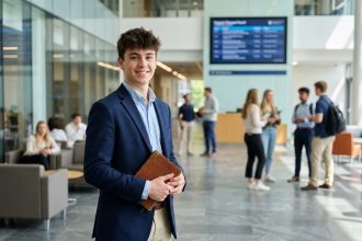 Jeune étudiant confiant dans un hall moderne d'école de commerce